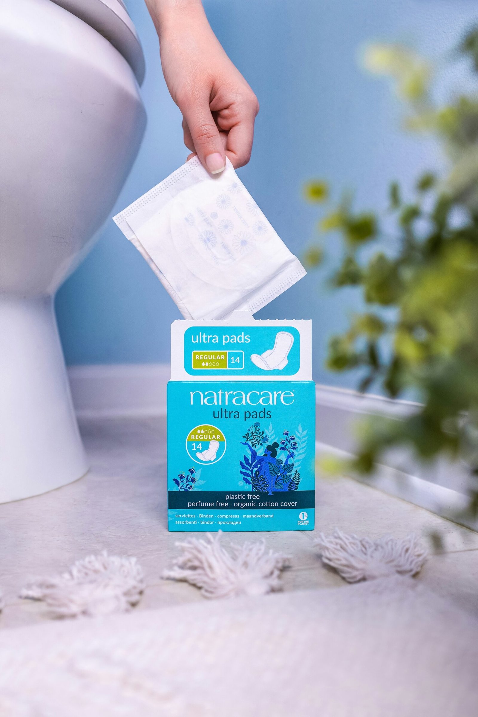 A person holding a packet of toilet paper in front of a toilet